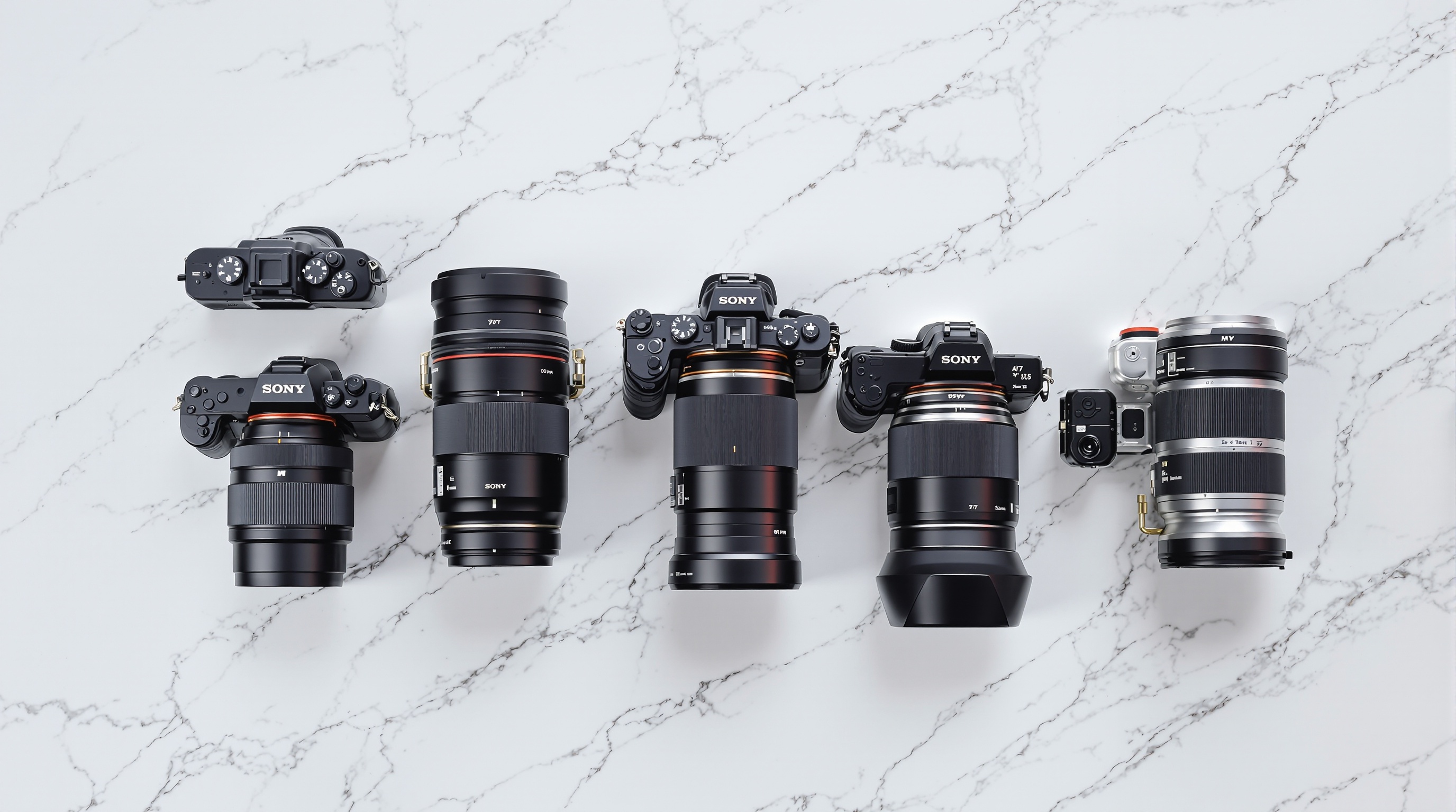 Row of different camera bodies and lenses arranged on a white marble surface with soft diffused studio lighting