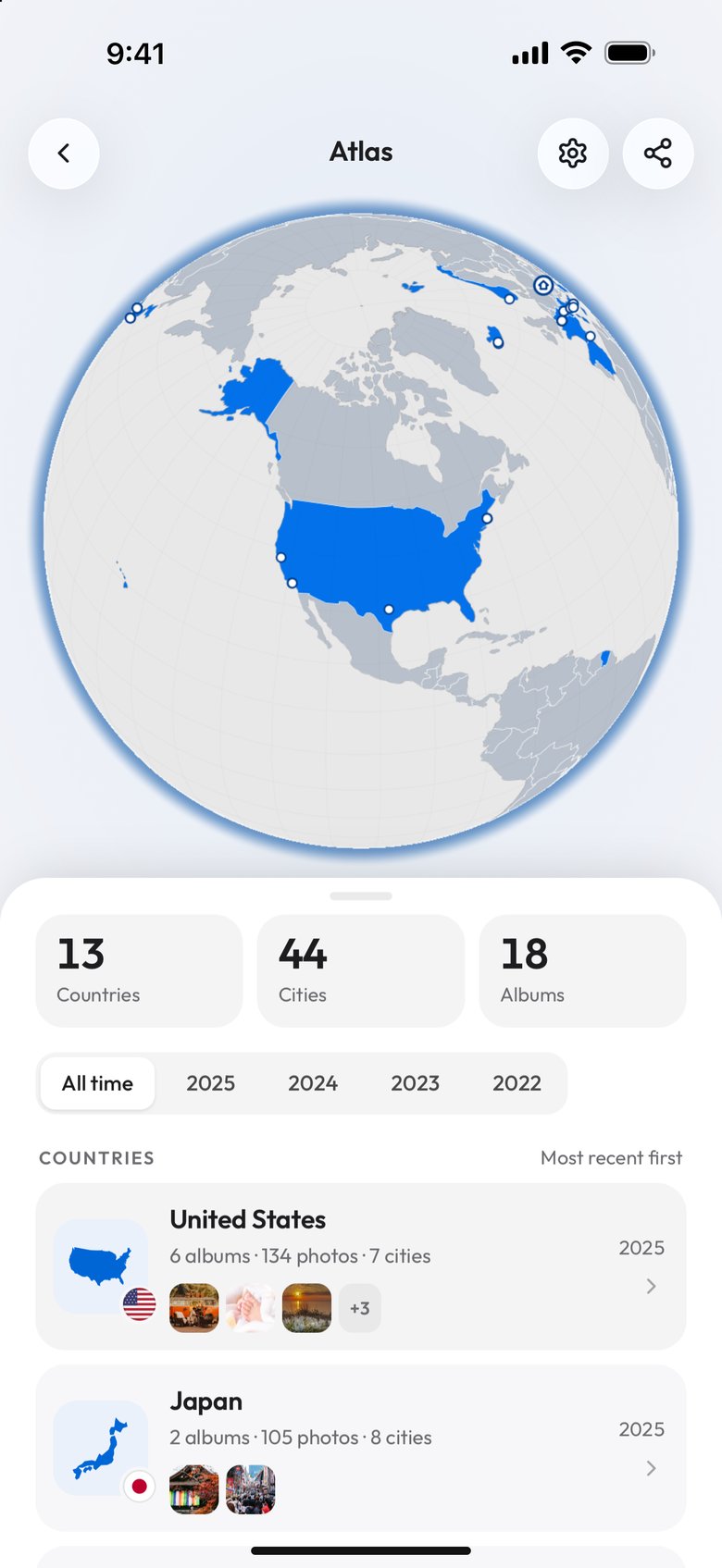 Viallo's Atlas on a phone: a globe turned to North America with the United States in blue and white dots on its cities, the tiles 13 Countries, 44 Cities and 18 Albums, the years All time to 2022, and the country list starting with the United States, 6 albums, 134 photos, 7 cities, and Japan, each with album covers