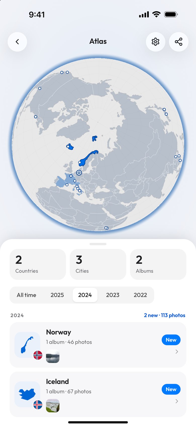 The Atlas on a phone with 2024 picked in the year row: the globe turned to the North Atlantic with Norway and Iceland in bright blue and the earlier countries in a paler blue, the tiles 2 Countries, 3 Cities and 2 Albums, the label 2 new, 113 photos, and Norway and Iceland each marked New