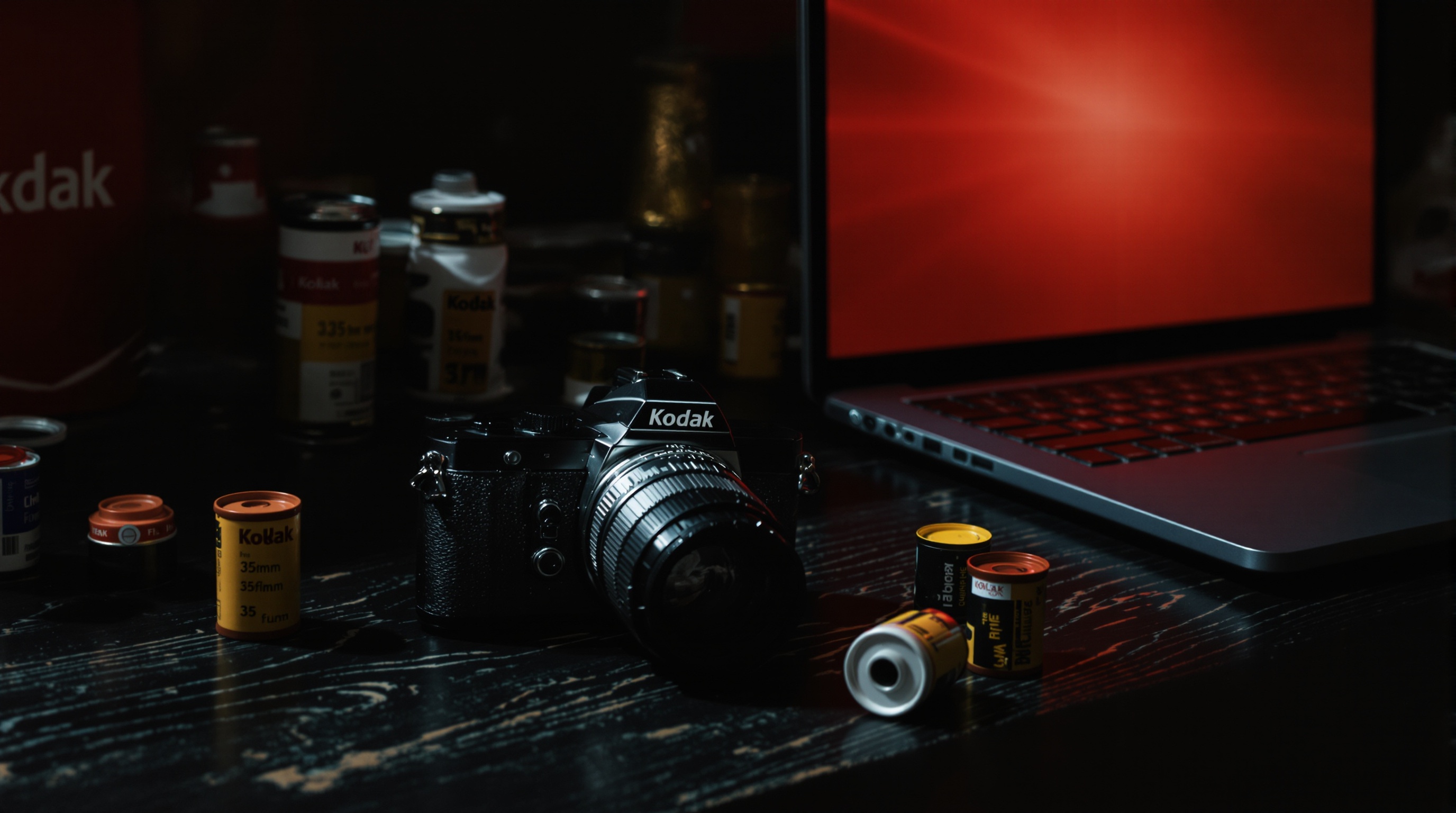 Vintage Kodak camera sitting on a desk next to scattered film rolls and a laptop showing a security alert