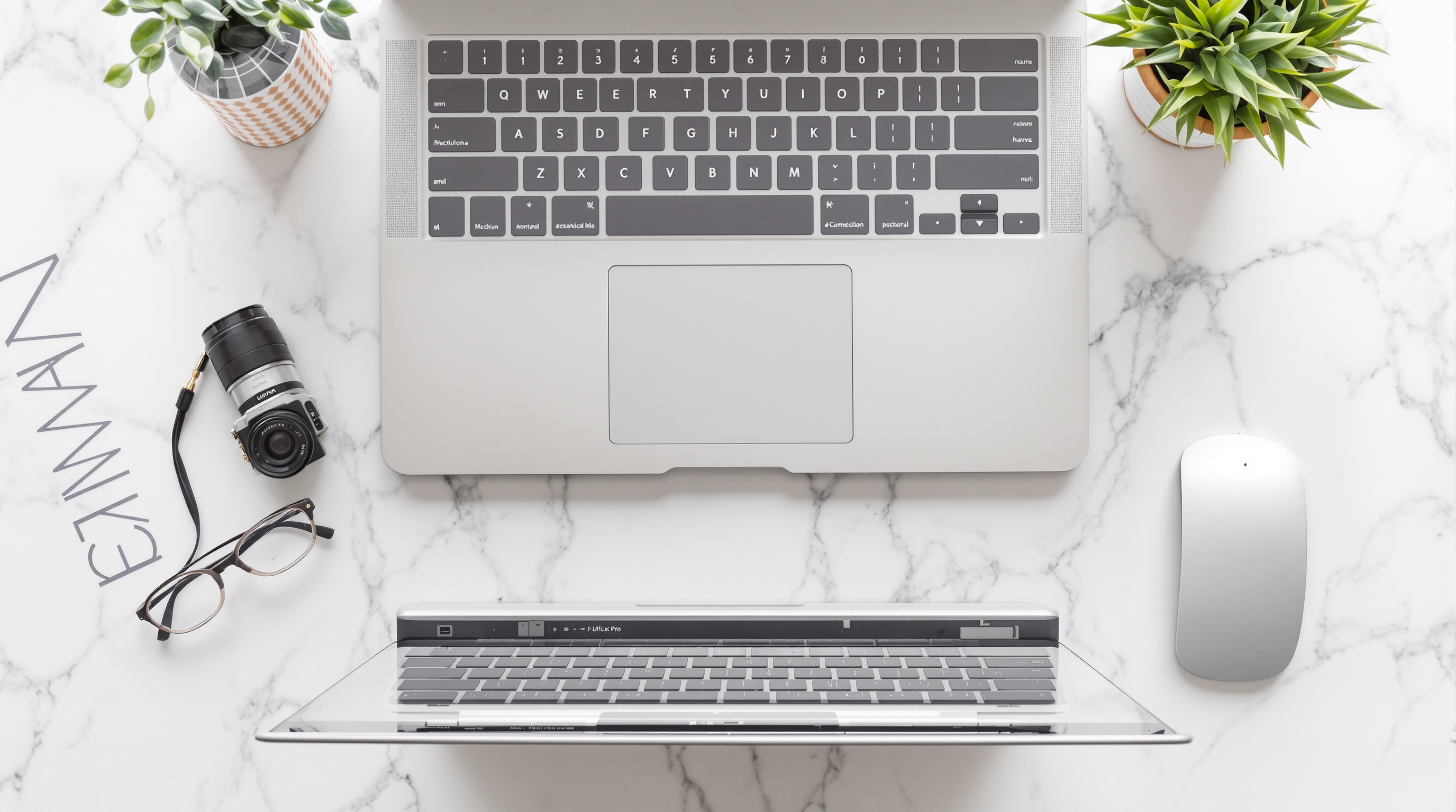 A laptop keyboard and desk setup with a camera nearby, representing editing photo metadata on desktop