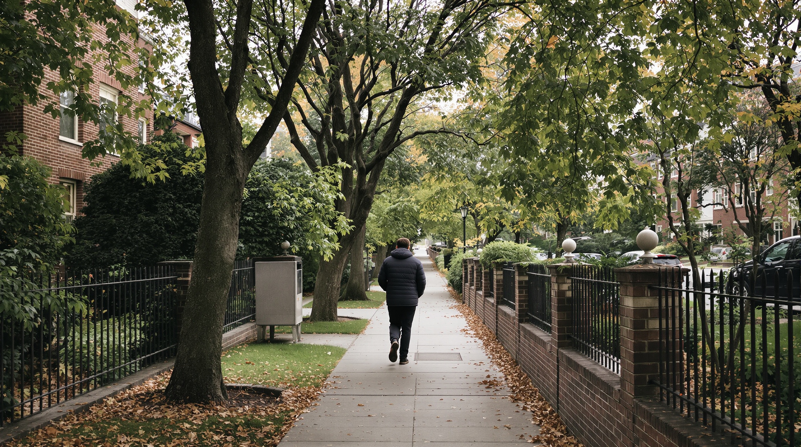 A person walking down a quiet residential street seen from behind with soft morning light